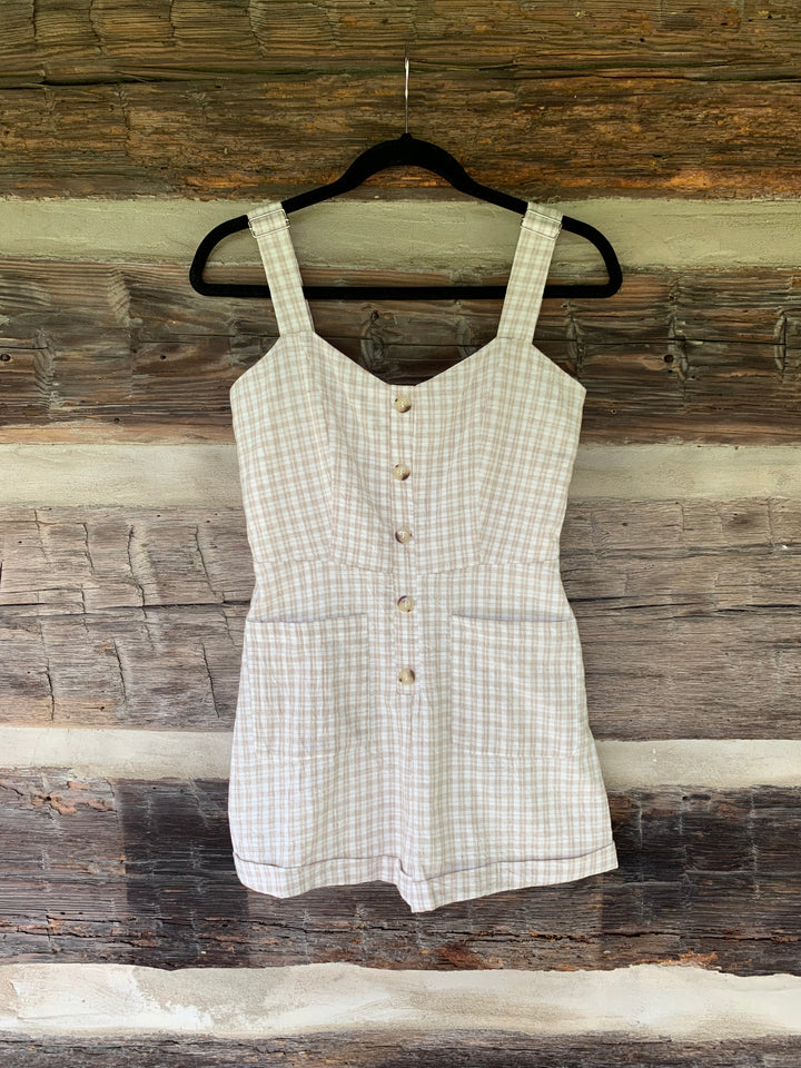 White checkered romper on a hanger against a wooden background