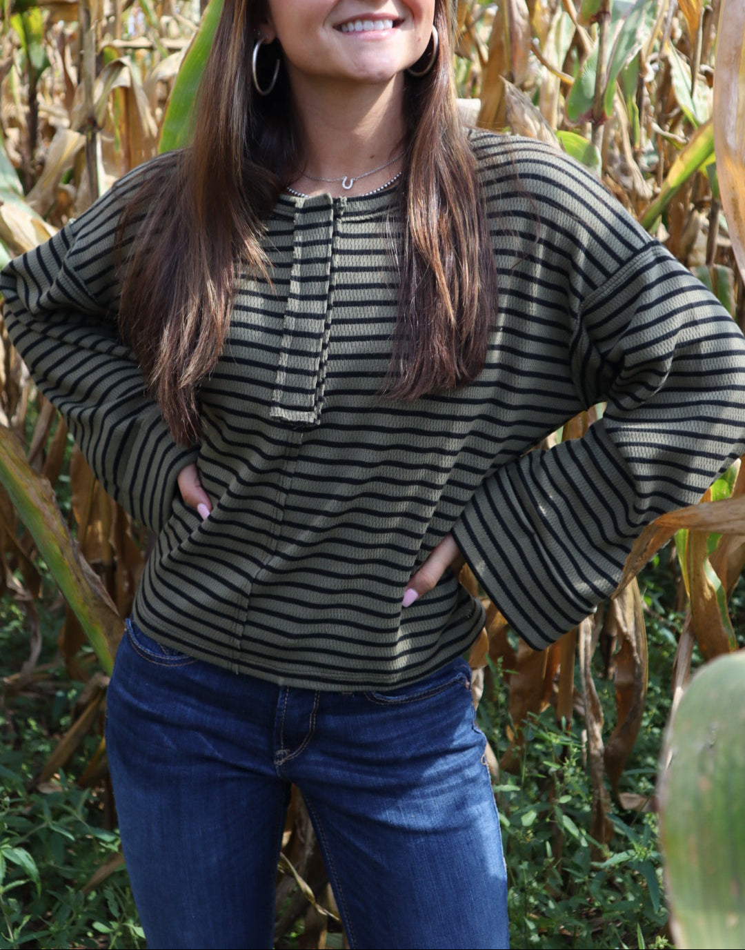 Woman wearing a striped sweater standing in a cornfield