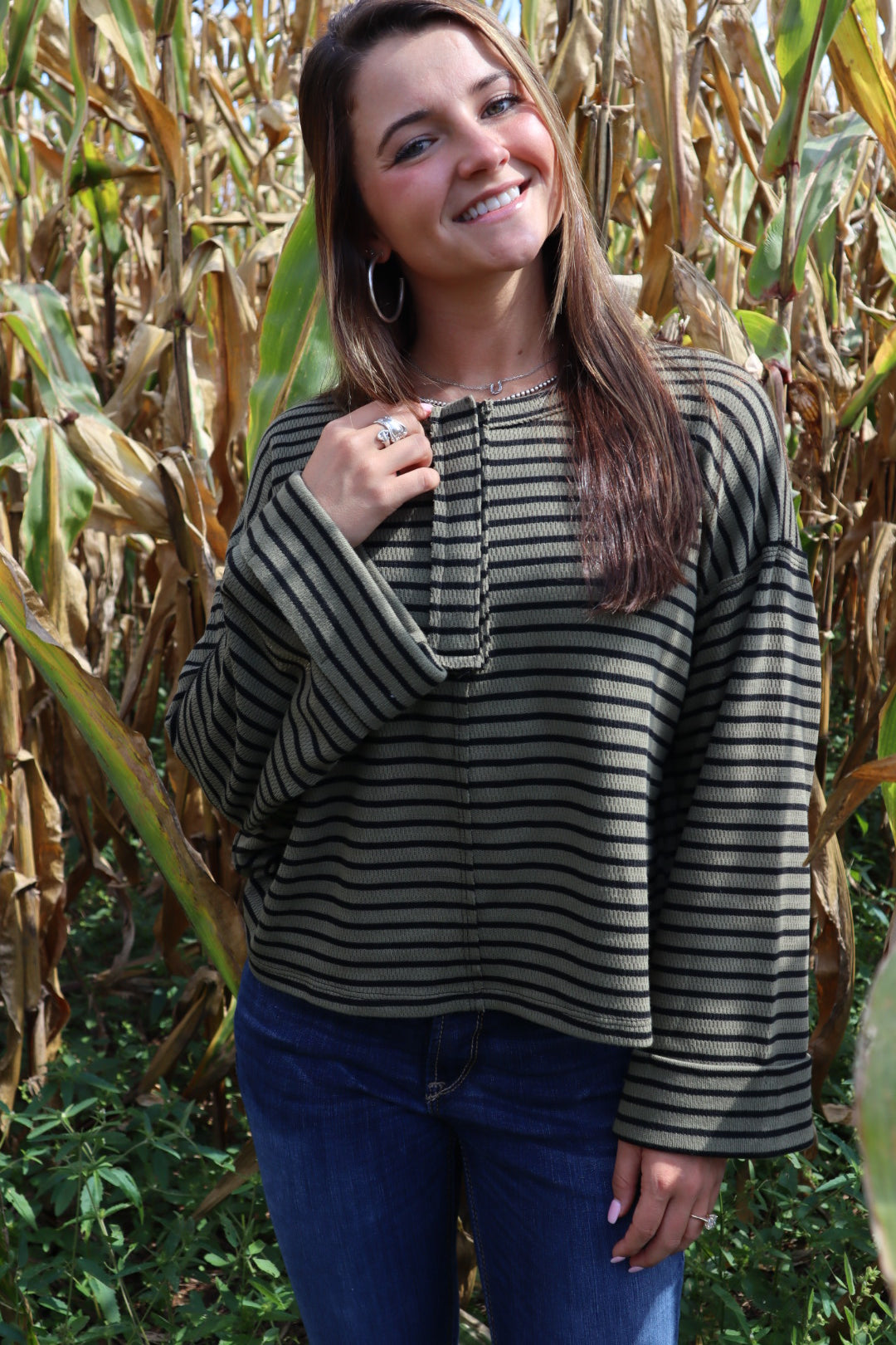 Woman wearing a striped coat standing in a cornfield